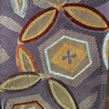 Close-up of a silk fabric with geometric patterns in purple, gold, and brown.