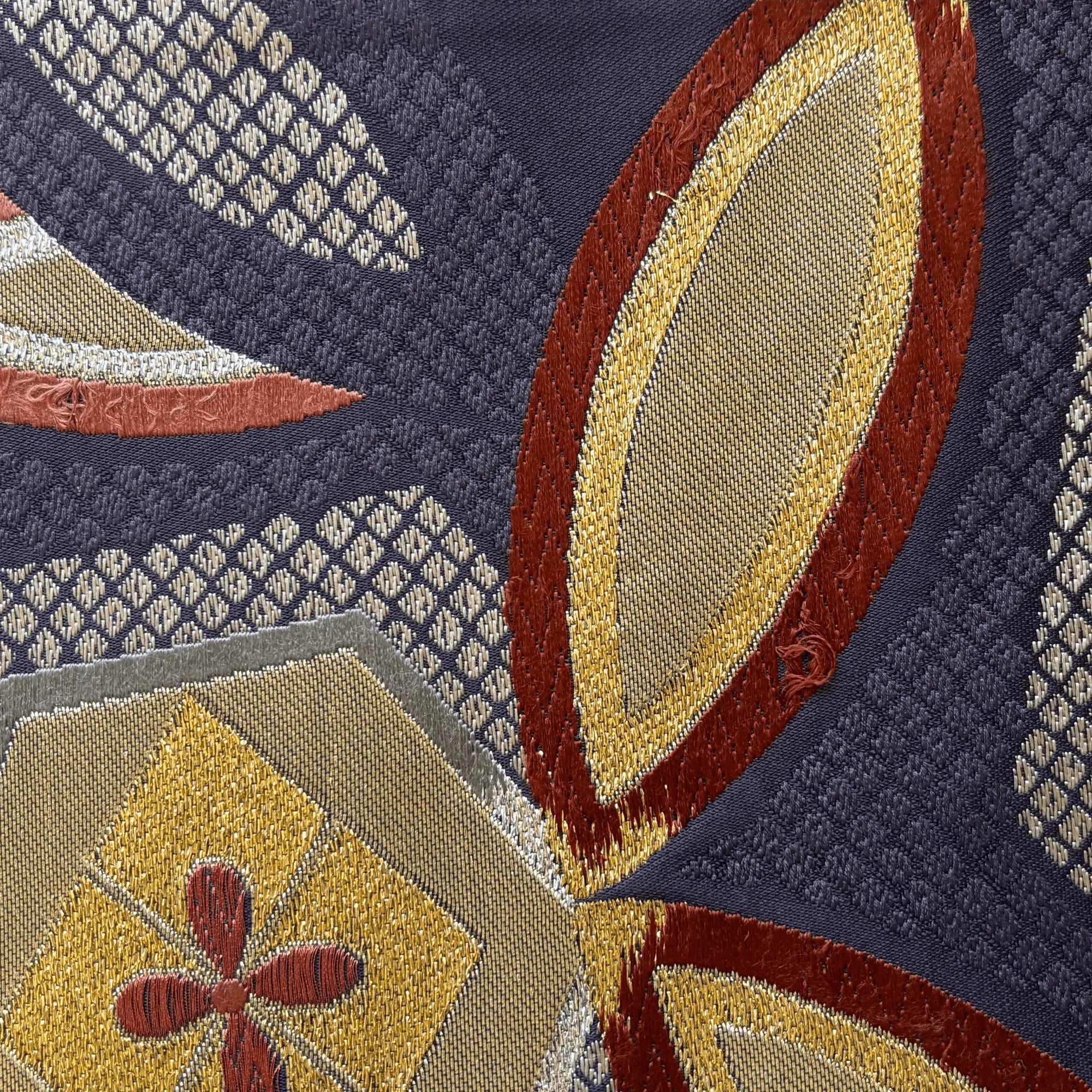 Close-up of a textured fabric with geometric patterns in red, yellow, and blue.