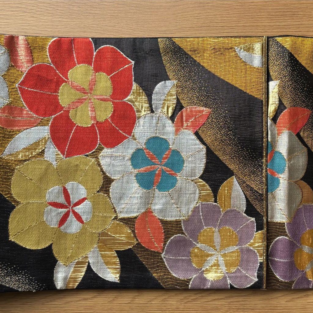 Decorative silk Obi with colorful floral patterns on a wooden surface