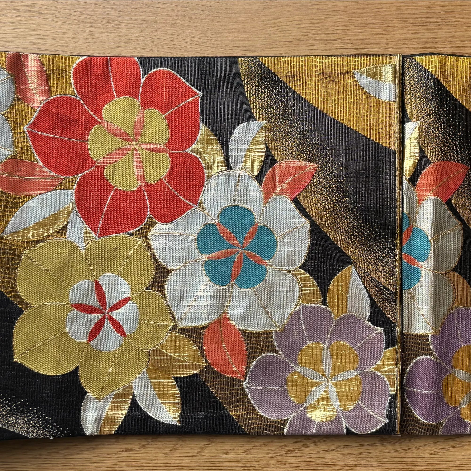 Decorative silk Obi with colorful floral patterns on a wooden surface