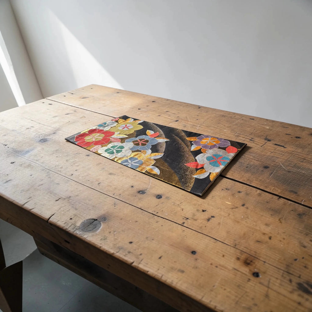 Floral silk Obi on a wooden table with a white wall background