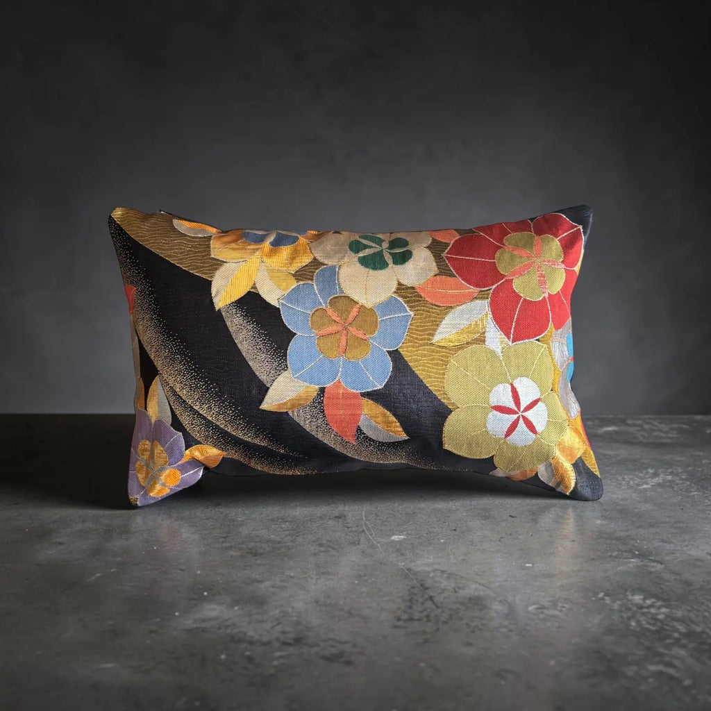 A rectangular decorative cushion with a floral pattern woven in gold.