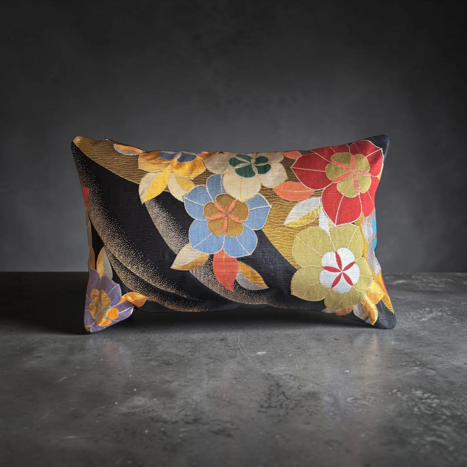 A rectangular decorative cushion with a floral pattern woven in gold.