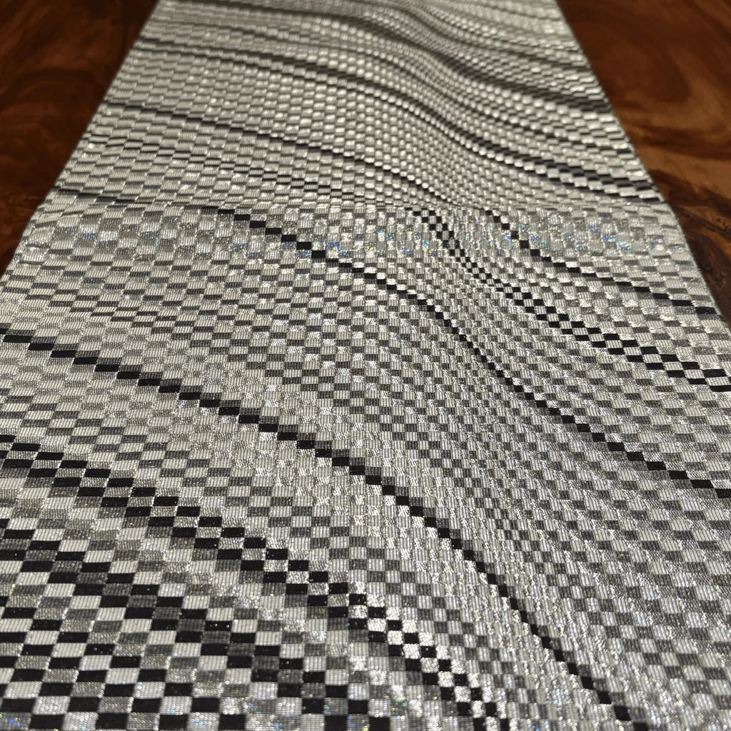 Close-up of a textured silver and black patterned rug on a wooden floor.