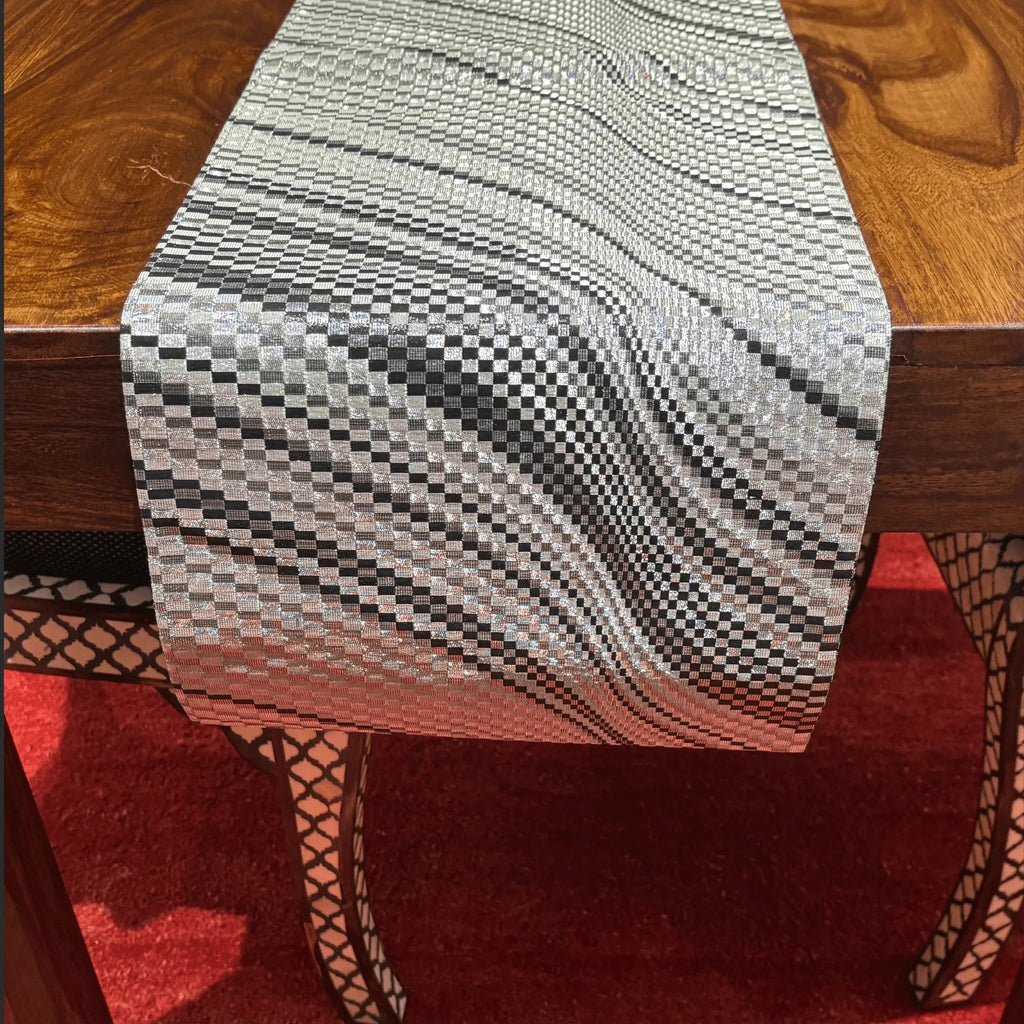 Textured table runner on a wooden table with a red rug underneath
