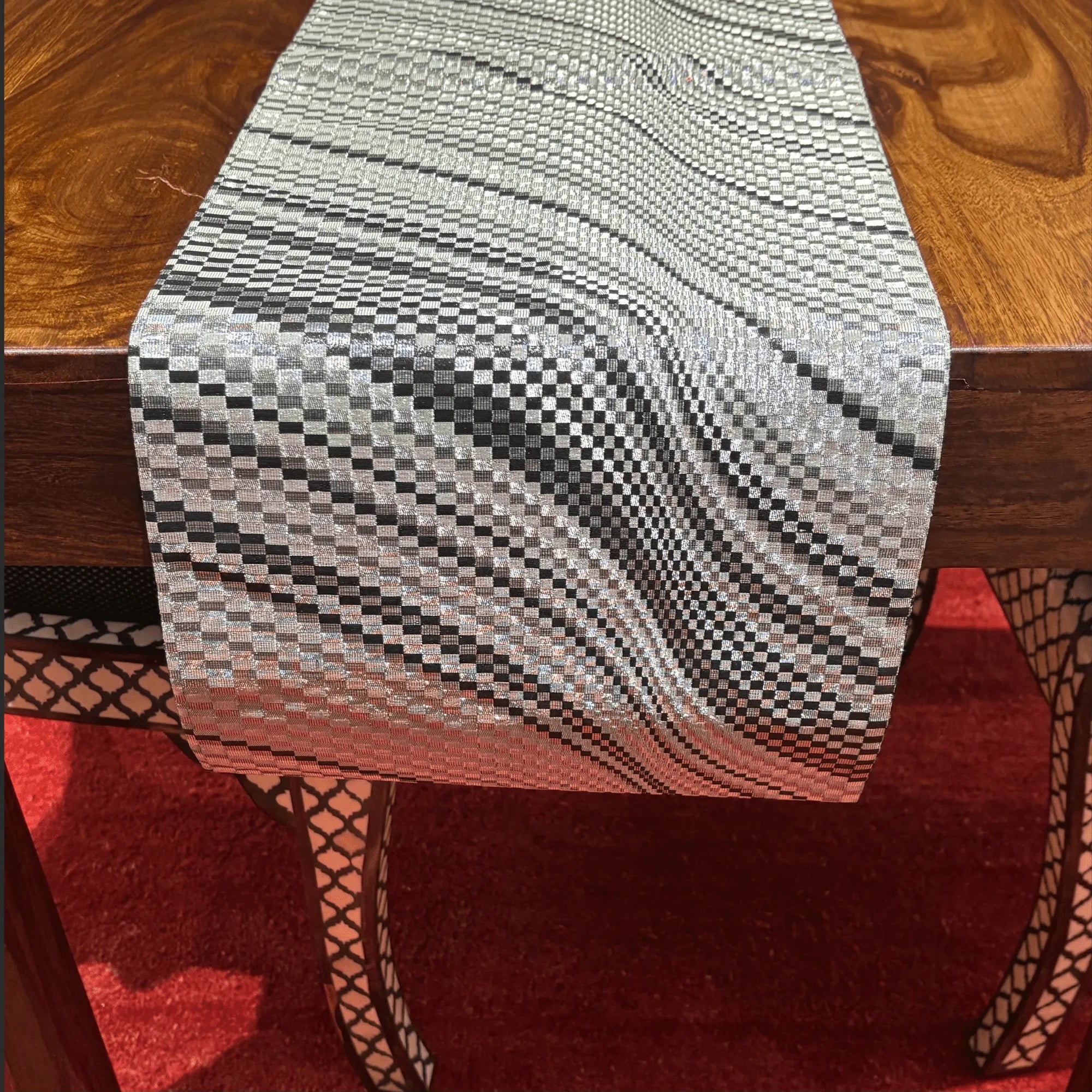 Textured table runner on a wooden table with a red rug underneath