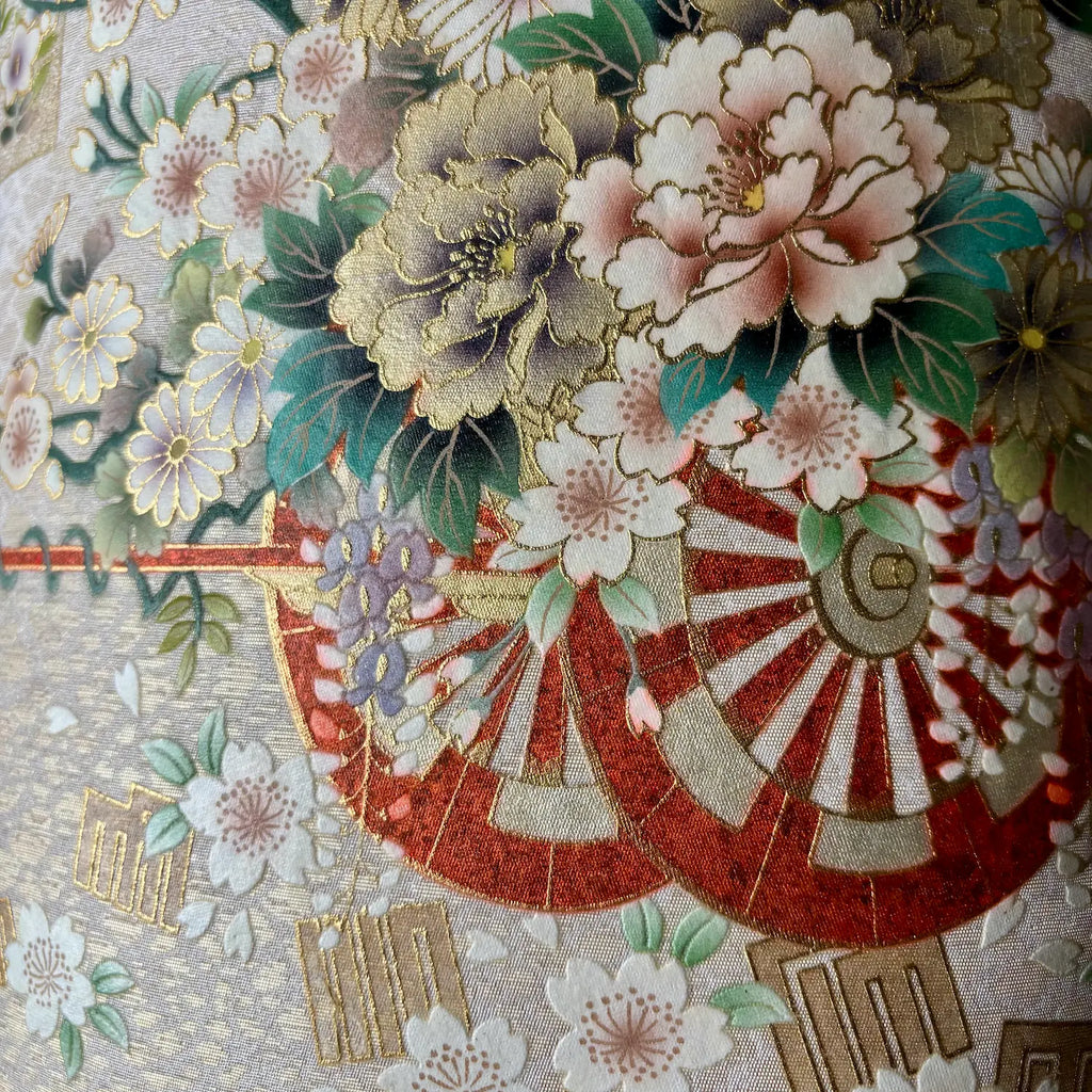 Close-up of a Japanese-style floral and fan pattern on fabric, featuring large peony-like flowers.