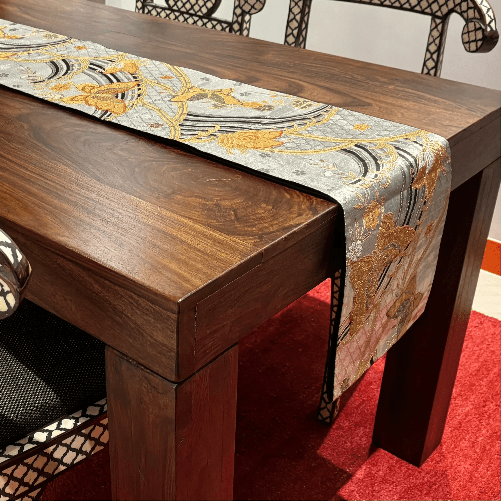 Wooden table with a decorative table runner on a red carpet
