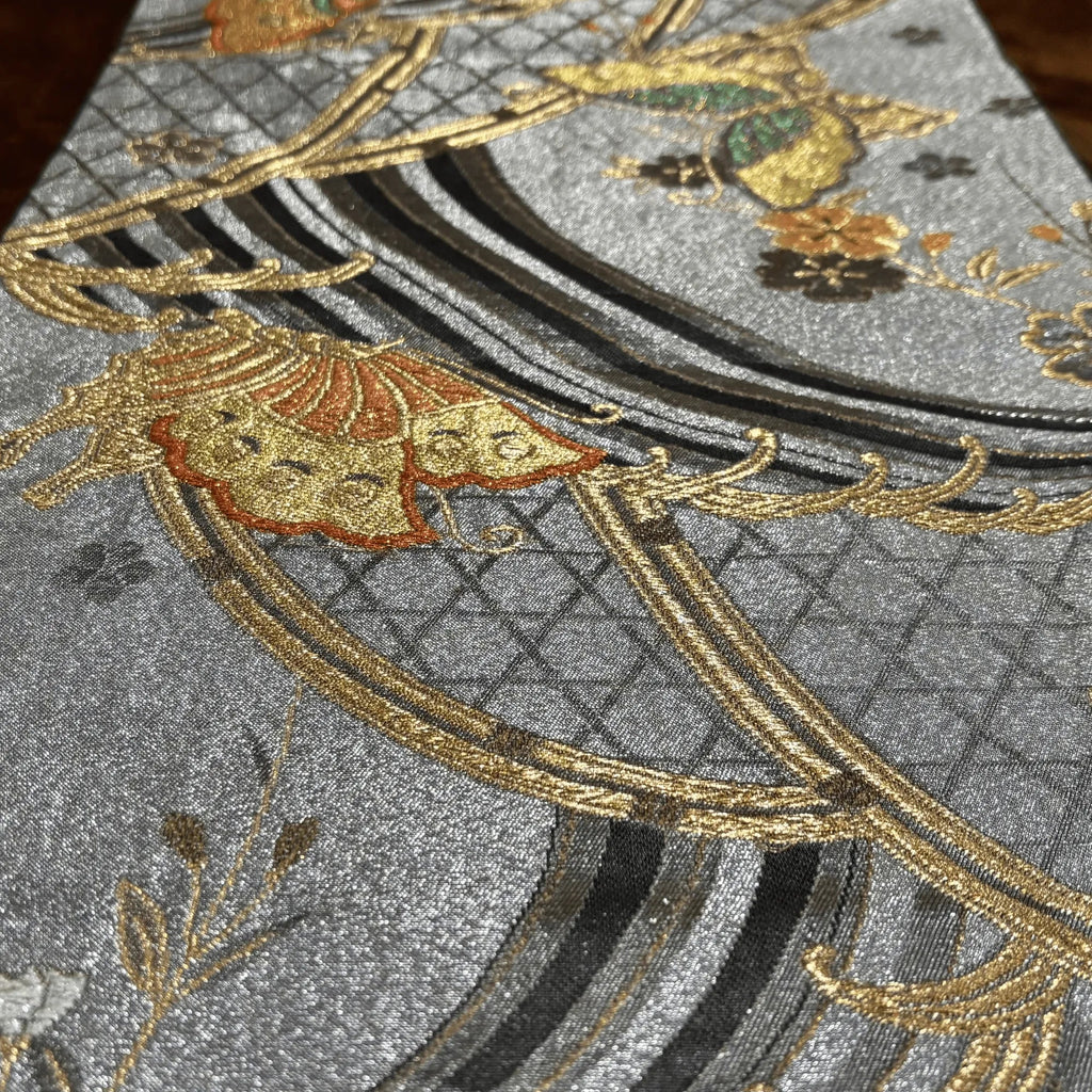 Close-up of embroidered fabric with gold and black patterns on a silver background