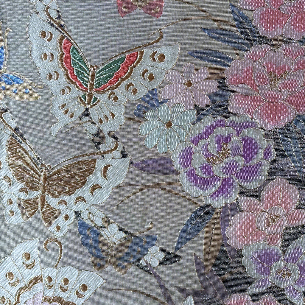 Decorative fabric with embroidered butterflies and flowers on a silver background