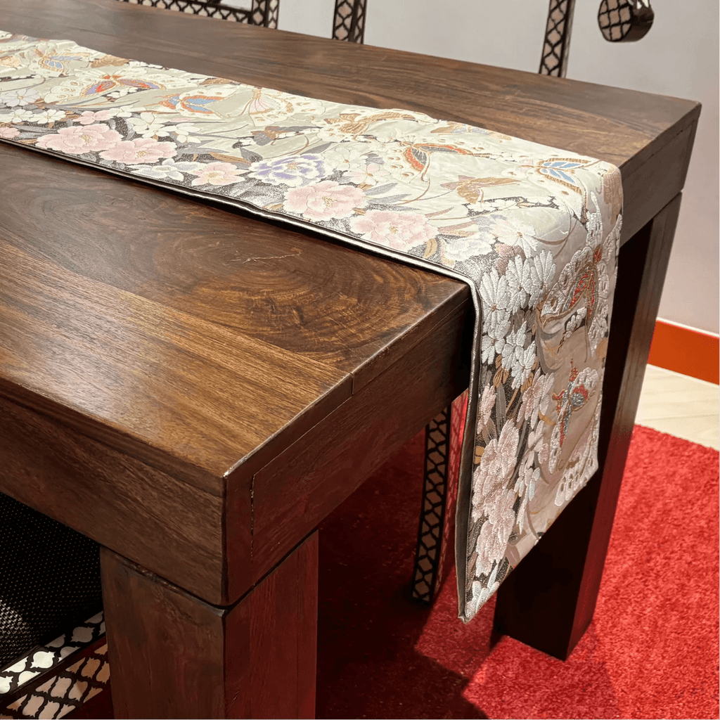 Wooden table with a floral-patterned table runner on a red carpet