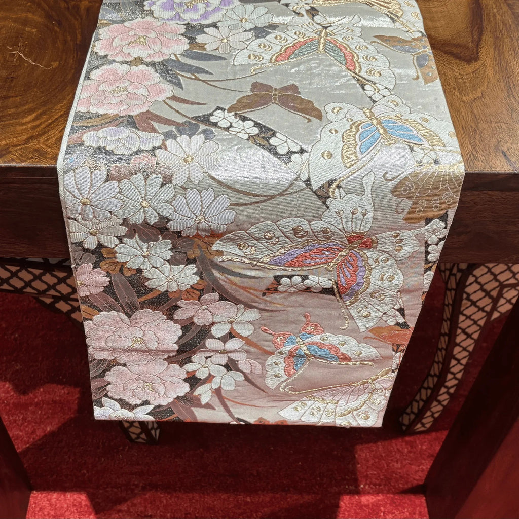 Decorative table runner with floral and butterfly pattern on a wooden surface.