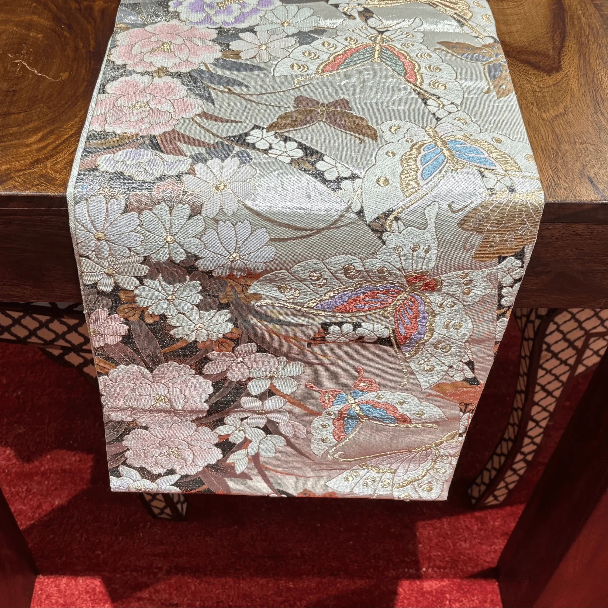 Decorative table runner with floral and butterfly pattern on a wooden surface.