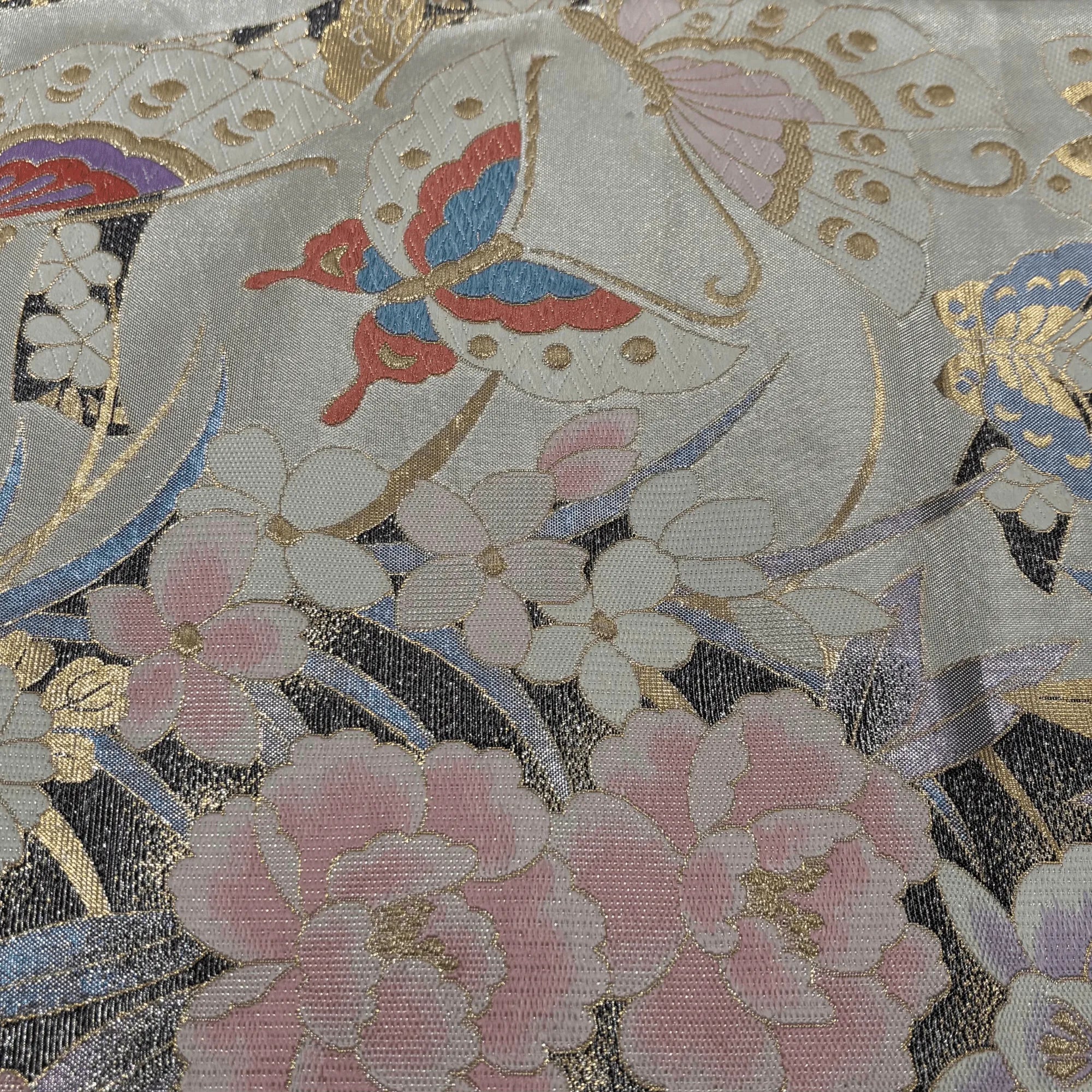 Decorative fabric with floral and butterfly patterns in soft colors.