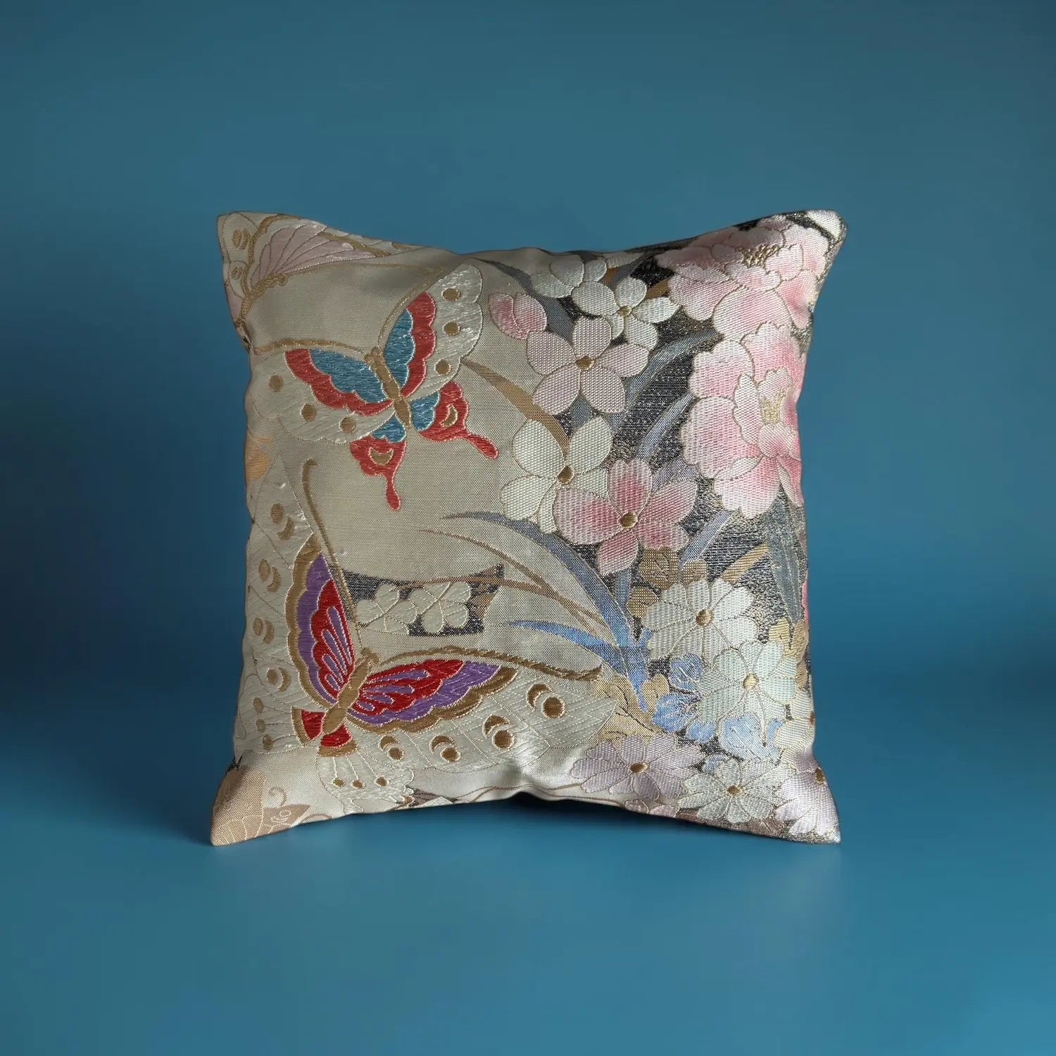 Decorative cushion with floral and butterfly pattern on a blue background